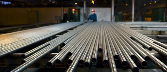 Pipes in row with workers in steel factory